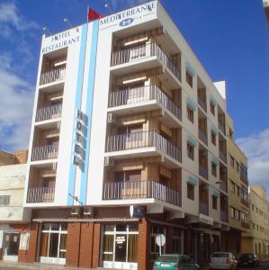 a tall white building with balconies on the side of it at Hotel Mediterranee in Nador