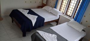 two twin beds in a room with a window at Palm View Residency in Varkala