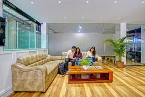 três pessoas sentadas num sofá numa sala de estar em Hotel Mild Inn em Calangute