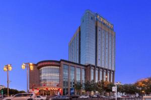 a tall building with cars parked in front of it at Datong Tiangui International Hotel in Datong