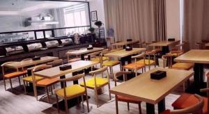 a restaurant with tables and yellow chairs in a room at GreenTree Inn Heze Railway Station Hotel in Zhaolou