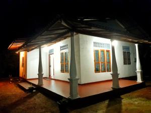a small white house with a porch at night at CYT VILLA - Ja Ela in Ja-Ela