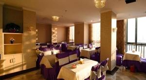 un restaurant avec des tables blanches et des chaises violettes dans l'établissement GreenTree Inn Anhui Hefei Tongda Road Wanhuan Shopping Plaza Business Hotel, à Hefei