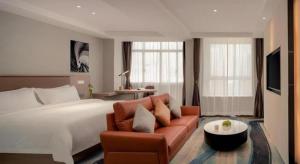 a hotel room with a bed and a couch at GreenTree Inn Ganzhou Sankang Temple DaRunFa Express Hotel in Ganzhou