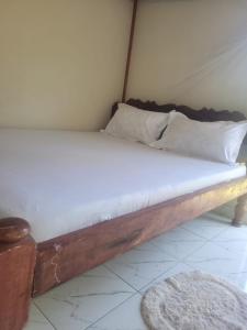 a bed with white sheets and pillows in a room at Cozy studio in Malindi