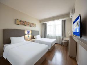 ein Hotelzimmer mit zwei Betten und einem Flachbildfernseher in der Unterkunft Hanting Hotel Beijing Daxing New Town Jinxing Bridge in Peking