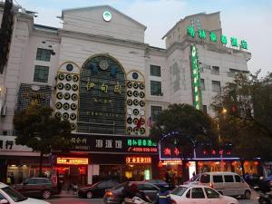ein großes Gebäude, vor dem Autos parken in der Unterkunft GreenTree Inn Shanghai Gongkang Road Branch in Jiangwan