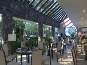 a restaurant with tables and chairs and a stone wall at Elmi Hotel in Surabaya