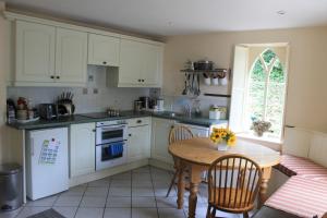 a kitchen with white cabinets and a table with chairs at Glyn Arthur Lodge in Llandyrnog