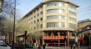 ein großes Gebäude an einer Stadtstraße mit Leuten davor in der Unterkunft Tianrun International Hotel in Dunhuang