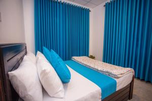 a bedroom with blue curtains and a bed with blue pillows at Amora Villa in Galle