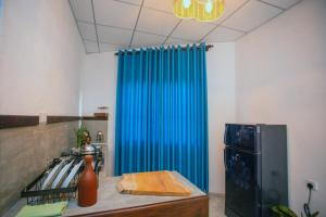 a kitchen with a blue curtain next to a refrigerator at Amora Villa in Galle