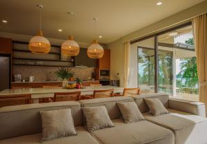 a living room with a couch and a kitchen at Treetop Bliss Villa by Sea N' Rent in Koh Phangan