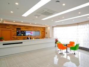 Eine Frau, die an einem Tresen in einer Krankenhauslobby sitzt. in der Unterkunft Vatica HeFei Baishuiba BHG Hotel in Hefei