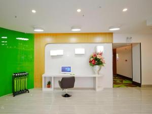 ein Büro mit einem Schreibtisch und einer Vase aus Blumen in der Unterkunft Vatica HeFei Baishuiba BHG Hotel in Hefei
