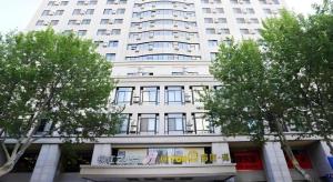 a large white building with trees in front of it at Jinjiang Inn Dalian Jiefang Road in Dalian