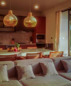 a living room with chairs and a kitchen with chandeliers at Treetop Bliss Villa by Sea N' Rent in Koh Phangan