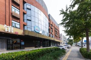 ein Gebäude an einer Straße, vor dem Autos parken in der Unterkunft Hanting Hotel Beijing Daxing New Town Jinxing Bridge in Peking