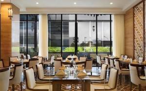 a restaurant with tables and chairs and a large window at Hotel Grandhika Pemuda in Semarang