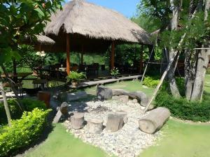 un jardin avec une grande cabane avec un foyer dans l'établissement Natura Maerim Resort, à Ban Nong Pla Man (1)
