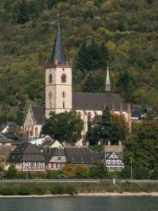 a large building with a clock tower next to the water at Ferienwohnung David in Lorch am Rhein