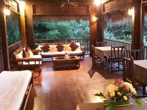ein Wohnzimmer mit einer Couch sowie Tischen und Stühlen in der Unterkunft Pai Hotsprings Spa Resort in Ban Tha Pai