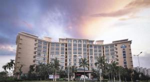 ein großes Gebäude mit Palmen davor in der Unterkunft Da Peng Zhongzhou Hotel in Haikou