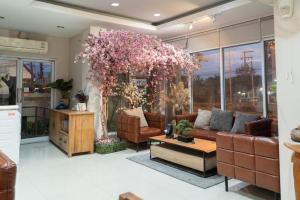 ein Wohnzimmer mit einem Sofa und einem Baum mit rosa Blumen in der Unterkunft Nonsi Hotel Phitsanulok in Ban Wat Tha Maprang