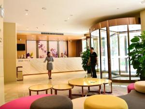 zwei Personen stehen in einer Lobby mit Tischen und Stühlen in der Unterkunft Lavande Hotel·Xishuangbanna Jinghong Songkran Square in Jinghong