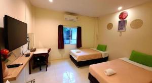 a room with two beds and a desk and a television at Green Home Resort in Surat Thani