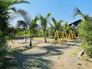 a playground with yellow swings and palm trees at Rama Hills Unity Resort in Kevadia