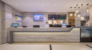 eine Frau steht an einer Theke in einem Restaurant in der Unterkunft City Comfort Inn Wuzhou Wangcheng Square in Wuzhou