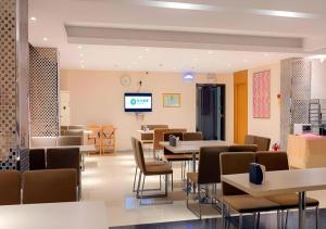 a waiting room with tables and chairs and a tv at City Comfort Inn Guigang Tangren Street in Guigang