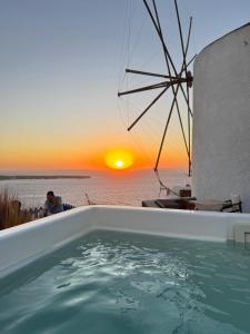 een hot tub met een zonsondergang op de achtergrond bij Lioyerma Windmill Villa With Outdoor Hot Tub in Oia