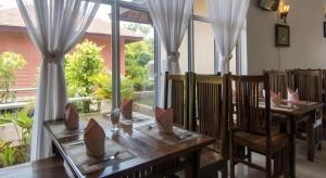 a dining room with a table and chairs and windows at Sambopich Chenla Hotel in Phumĭ Achary Leăk