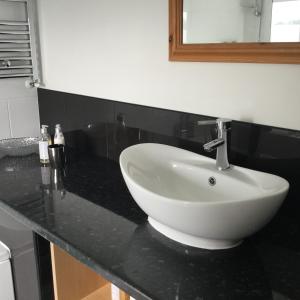 Llanwrtyd WellsにあるMaes y Gwaelodのバスルーム(白い洗面台、黒いカウンター付)
