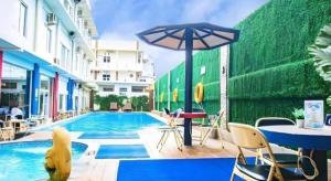 einen Pool mit einem Tisch und einem Sonnenschirm in der Unterkunft Hotel Grand Permata Hati in Geutieue