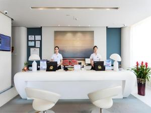 zwei Männer sitzen mit Laptops an einem großen Schreibtisch in der Unterkunft Jinjiang Metropolo Hotel - Qingdao Chengyang District Government in Qingdao