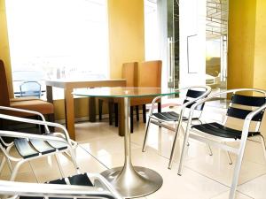 a dining room with a glass table and chairs at Metro Hotel in Surabaya