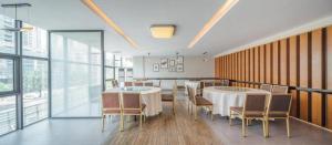 ein Esszimmer mit Tischen und Stühlen und Fenstern in der Unterkunft Zhaoqing Shanshui Fashion Hotel Duanzhou Road Branch in Zhaoqing