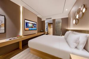 ein Schlafzimmer mit einem großen weißen Bett und einem Fernseher in der Unterkunft Orange Hotel, Beijing Daxing Biomedicine Base in Peking
