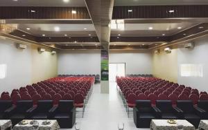 an empty auditorium with red chairs in a room at Flamengo Hotel in Gedeg