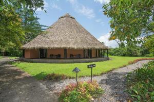 a hut with a thatched roof in a park at Aranwa Sarapiquí Rainforest Lodge in Sarapiquí