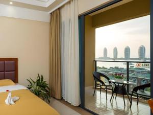 a bedroom with a bed and a table with chairs at Mango Sea View Hotel in Sanya