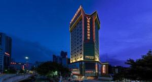 ein hohes Gebäude mit Lichtern in der Nacht in der Unterkunft Out Sky Hotel in Huizhou