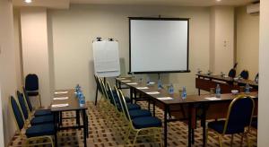 a conference room with a long table with chairs and a screen at D'Anaya Hotel Bogor in Bogor +144 photos