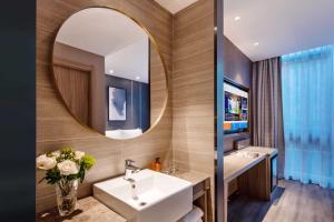 ein Badezimmer mit Waschbecken und Spiegel in der Unterkunft Orange Hotel, Beijing Daxing Biomedicine Base in Peking + 20 Fotos