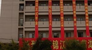 ein hohes Gebäude mit roten und orangefarbenen Bannern darauf in der Unterkunft Jinjiang Inn Wuhu High-Speed Railway Station West Square in Wuhu