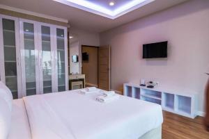 a bedroom with a white bed and a television at At Home at Udon in Udon Thani