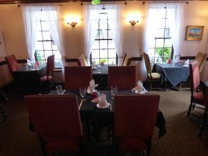 un comedor con mesas, sillas y ventanas en Old City House Inn and Restaurant en Saint Augustine